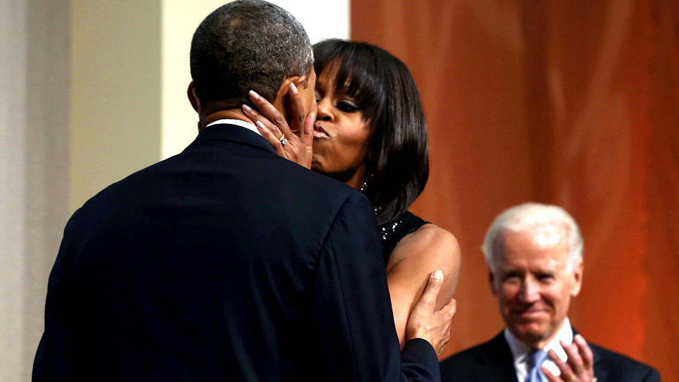 उदघाटन समारोह के दौरान बराक ओबाका का चुंबन से अभिवादन करते हुए उनकी पत्नी मिशेल ओबामा. साथ में खड़े हैं उपराष्ट्रपति जोज़ेफ बिदेन.  
