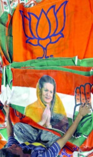 A worker looks at a Congress party flag carrying a picture of Gandhi next to flags of India's BJP inside an election campaigning material workshop on the outskirts of the western Indian city of Ahmedabad